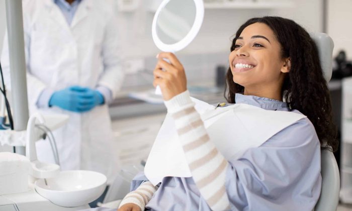 Happy,Black,Female,Patient,Looking,At,Mirror,After,Dental,Treatment